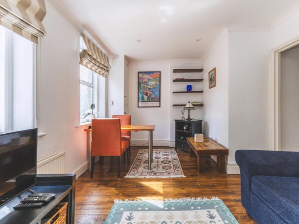Un salon comprenant un téléviseur, un canapé, une table à manger, des chaises et un tapis.