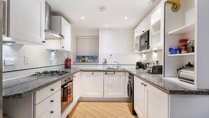 Eine moderne Küche mit weißen Schränken, Granit Arbeitsplatten, einer eingebauten Mikrowelle und einem Geschirrspüler.