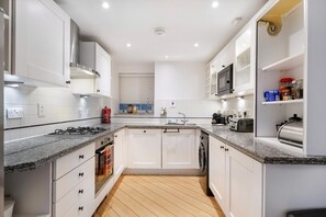 Eine moderne Küche mit weißen Schränken, Granit Arbeitsplatten, einer eingebauten Mikrowelle und einem Geschirrspüler.