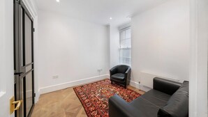 Ein Zimmer mit Teppichmuster, einem schwarzen Ledersessel, einer schwarzen Ledersofa und einer Tür mit Griff.