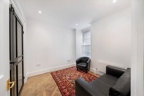 Ein Zimmer mit Teppichmuster, einem schwarzen Ledersessel, einer schwarzen Ledersofa und einer Tür mit Griff.