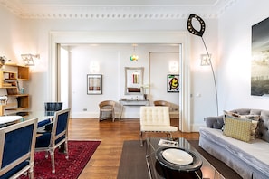 A living room with a dining area, a sofa, a coffee table, and a red rug. - Boutique Kensington Retreat Near Museums (London)