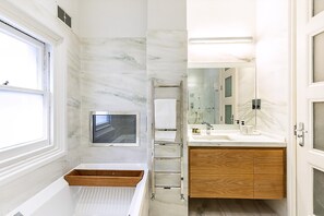 A bathroom with a marble wall, a wooden vanity, a built-in window, and a towel rack. - Boutique Kensington Retreat Near Museums (London)