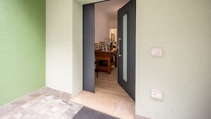 Un pasillo con piso de madera, una puerta y una pequeña mesa con objetos encima.