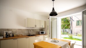 Una cocina con armarios blancos, encimera de madera, microondas y un comedor con mesa y sillas.