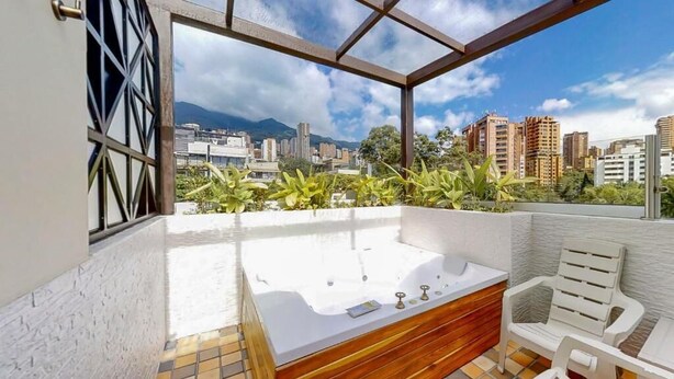 Terraza en la azotea con jacuzzi, zona de estar y vistas a la ciudad.