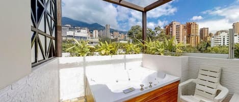 Terraza en la azotea con jacuzzi, zona de estar y vistas a la ciudad.