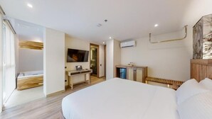 Habitación de hotel con una cama grande, un escritorio, un televisor y un baño con ducha e inodoro.