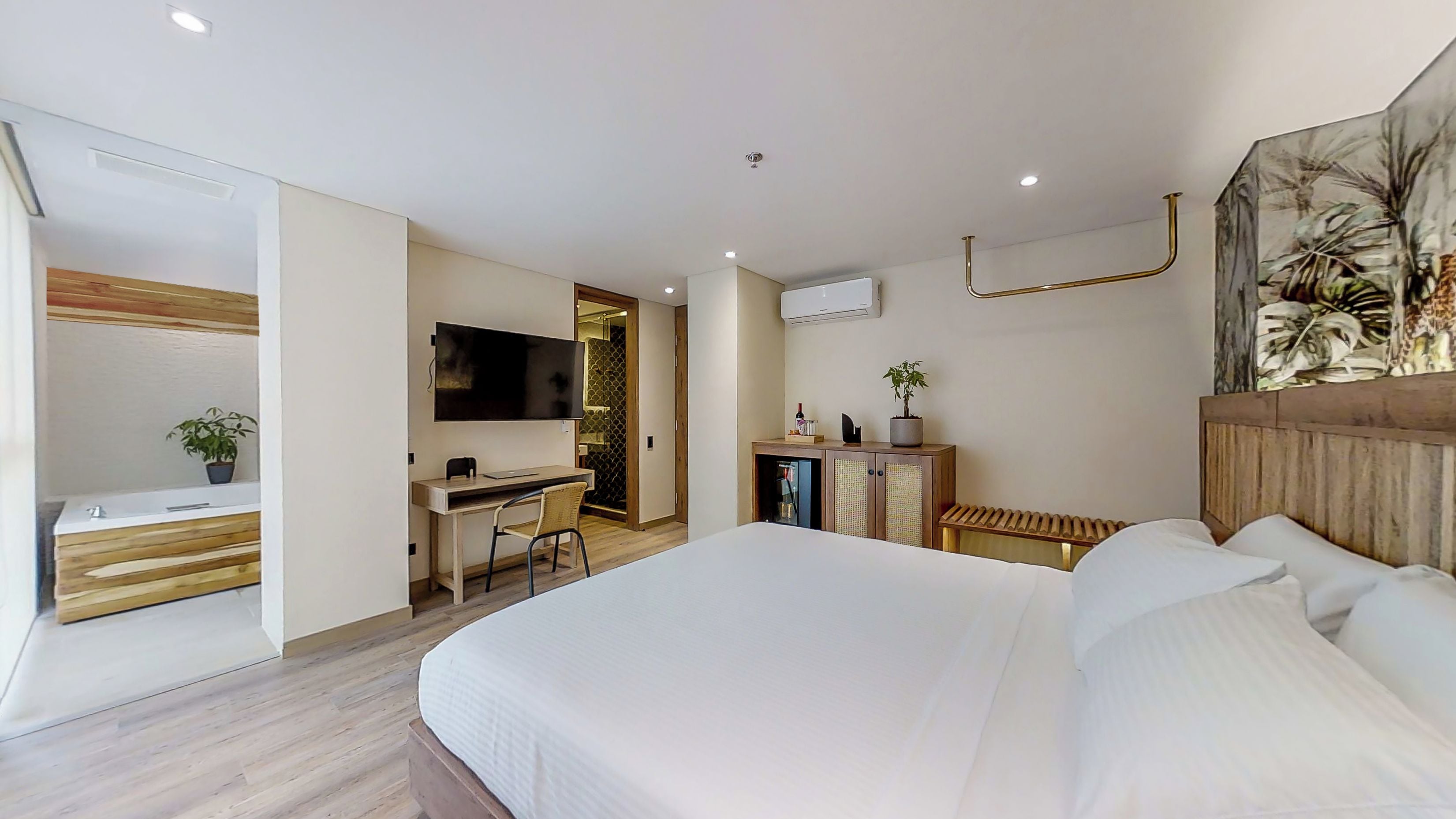 Habitació d'hotel moderna amb un llit gran, un escriptori amb una cadira, una televisió i un petit armari.