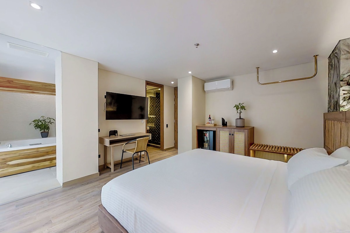 A modern hotel room with a large bed, a desk, and a television.