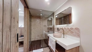 A modern bathroom with a glass-enclosed shower, a white sink with a round basin, and a large mirror above the sink. - Origen Hotel Boutique (Medellín)