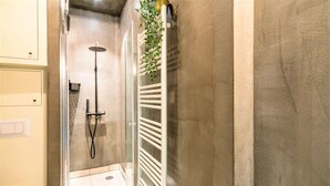 Ein Badezimmer mit Duschkabine aus Glas, einem Handtuchhalter und einer kleinen Pflanze.
