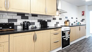A modern kitchen with wooden cabinets, a black countertop, and a built-in oven. - Bayview Aparthotel by Guestz (Morecambe)
