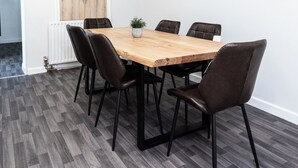 A dining area with a wooden table, black chairs, and a potted plant. - Bayview Aparthotel by Guestz (Morecambe)