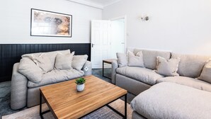 A living room with a grey sofa, a wooden coffee table, and a framed picture on the wall. - Bayview Aparthotel by Guestz (Morecambe)