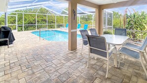 Eine überdachte Terrasse mit Pool, Sitzgelegenheiten im Freien und Deckenventilator.