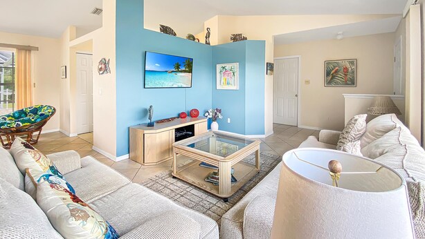 Ein Wohnzimmer mit Sofa, Sessel, Couchtisch, Fernseher und Dekoration.