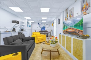 A modern living room with a sofa, yellow armchair, and a TV displaying a scenic landscape. - Cozy 6PPL Waterfront Cabin: BBQ, Firepit & Fishing (Port Richey)