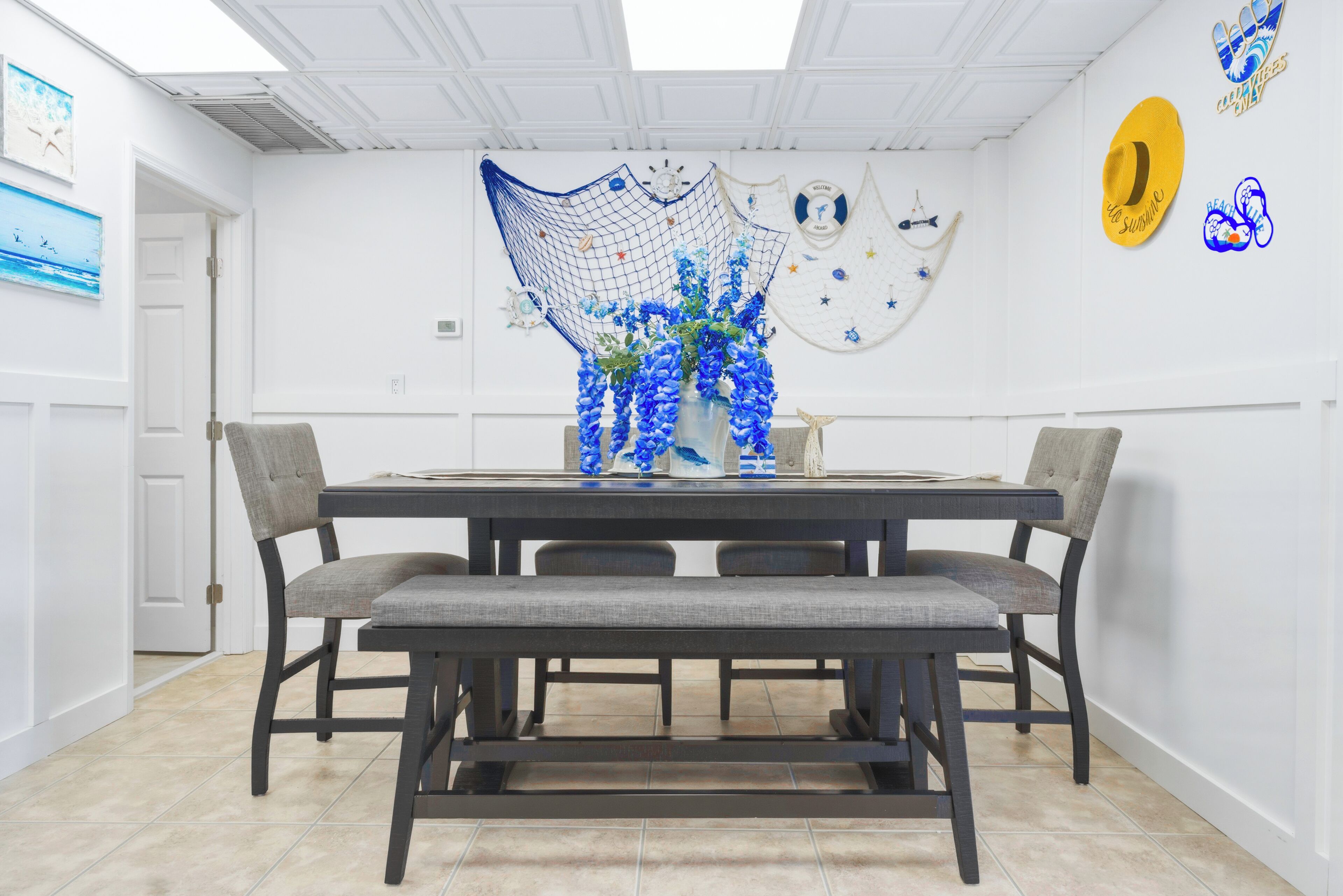A dining area with a dark wooden table, grey upholstered chairs, and a bench.