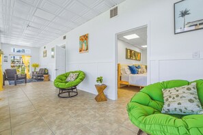 A spacious room with a green chair, a bed with pillows, and a painting on the wall. - Cozy 6PPL Waterfront Cabin: BBQ, Firepit & Fishing (Port Richey)