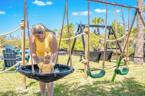 A playground with swings and a rope swing. - Cozy 6PPL Waterfront Cabin: BBQ, Firepit & Fishing (Port Richey)