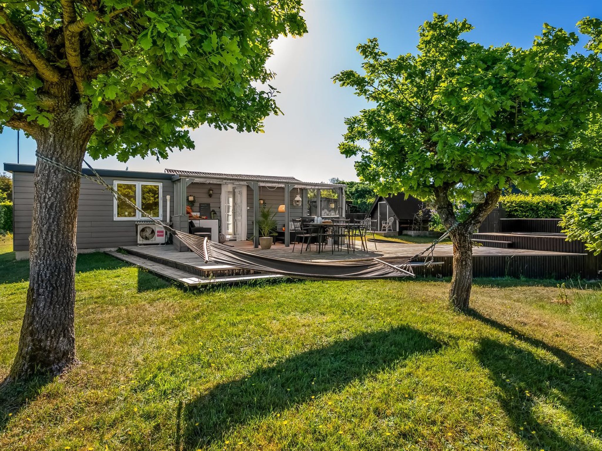 A modern outdoor living area with a deck, seating, and a hammock.