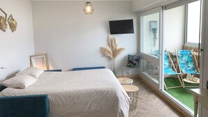 A bedroom with a bed, a TV, a window, and a balcony with chairs. - The horizon - Ocean view with magnificent sunset (Saint-Hilaire-de-Riez)