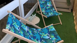 Two wooden lounge chairs with floral upholstery, a glass door, a small wooden bench, and a wall-mounted planter. - The horizon - Ocean view with magnificent sunset (Saint-Hilaire-de-Riez)