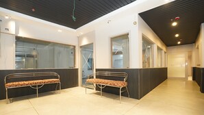 A reception area with two metal benches, a tiled floor, and a modern ceiling with recessed lighting. - Bidesh Ghar Hotel (Puri)