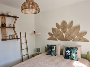 Une chambre à coucher avec un lit, des oreillers, un luminaire suspendu, une étagère fixée au mur et une échelle.