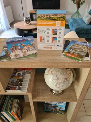 Une étagère en bois avec des brochures de voyage, un globe terrestre et une statuette de hibou décorative.