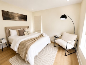A bedroom with a bed, bedside tables, a chair, a floor lamp, and a painting on the wall. - Muse Atelier | Houston (Houston)