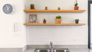 A kitchen with a double sink, white brick backsplash, and two wooden shelves with potted plants. - Nice City View Apartment in Escalon! (San Salvador)