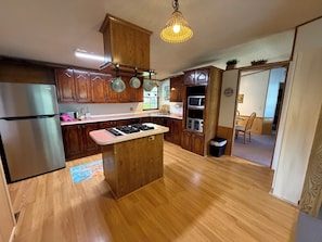 Eine Küche mit Holzausstattung, einem Edelstahl-Kühlschrank, einem Gasherd und einer Mikrowelle.