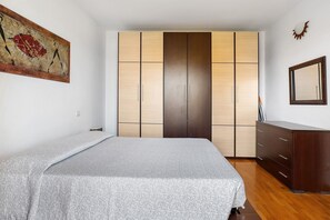 A bedroom with a bed, a wardrobe, a dresser, and a painting on the wall. - Apartment 'Gigli Vista Lago' with Lake View, Wi-Fi and Air Conditioning (Lazise)