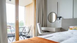 Een hotelkamer met een bed, bureau, stoel, spiegel en uitzicht op de omgeving.