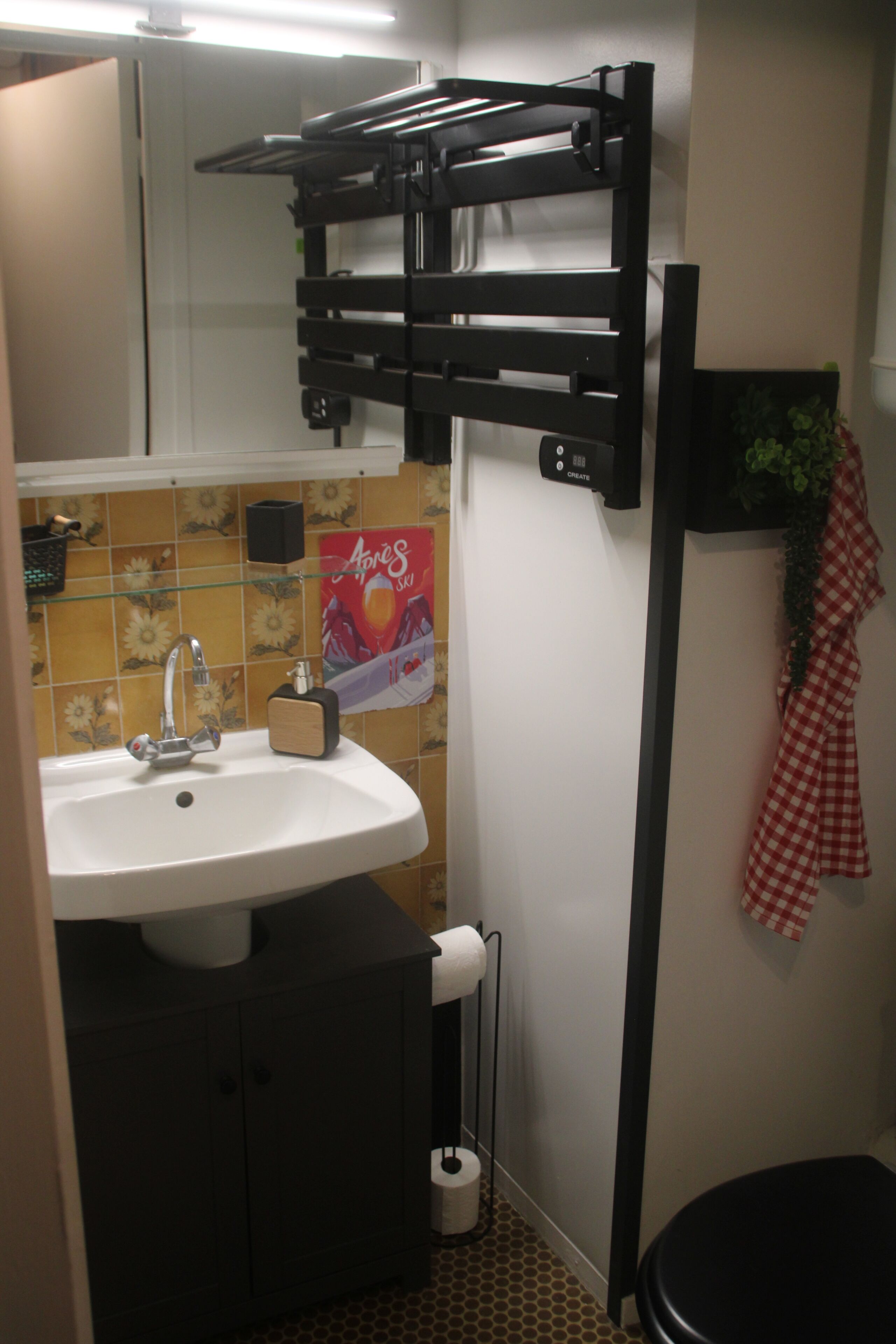 A bathroom with a white sink, a black towel rack, a toilet, and a shower area.