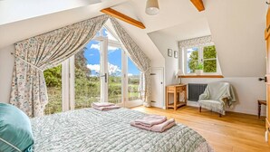 A bedroom with a large bed, a radiator, a window with curtains, and a view of the outdoors. - The Stag in the Chiltern Hills (Fawley)