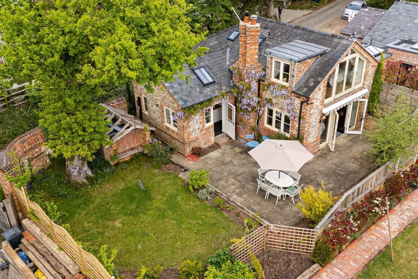 A two-story house with a brick exterior, a visible chimney, and a patio with outdoor furniture.