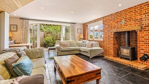 A cozy living room with a brick fireplace, a sectional sofa, and a wooden coffee table. - The Stag in the Chiltern Hills (Fawley)