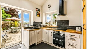 A kitchen with white cabinets, a black stove, and a black backsplash. - The Stag in the Chiltern Hills (Fawley)