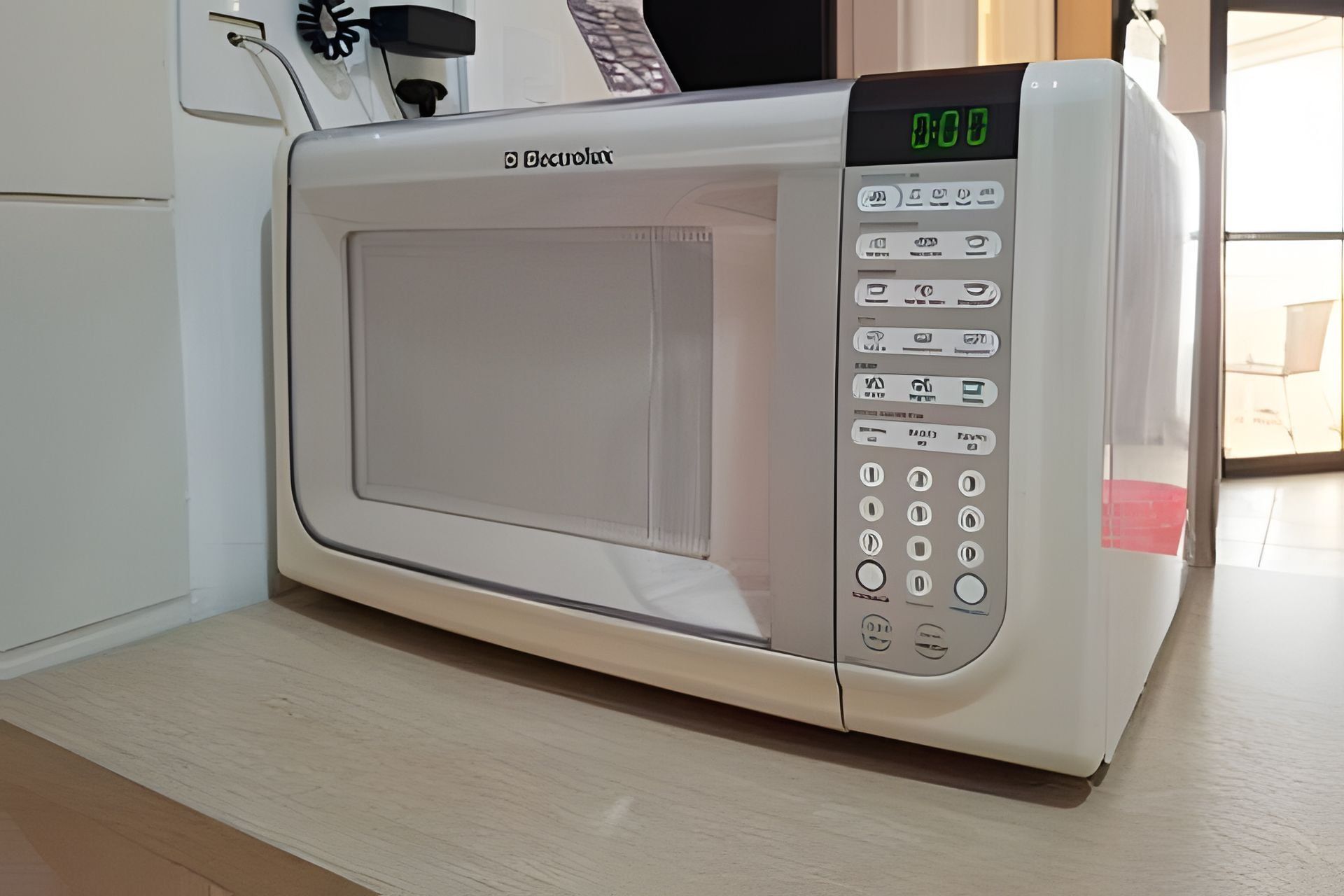 Een witte magnetron met een digitaal display en meerdere bedieningsknoppen op een aanrecht.