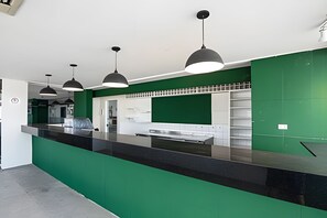 A modern kitchen with a black countertop, green backsplash, and pendant lighting. - SHB - Entre a Praia e o Mundo Disney (Santos)