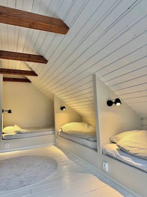 A compact attic bedroom with two bunk beds, wooden beams, and wall-mounted lighting. - Cozy Cottage in top Condition Close to Nature and Lakes (Jonkoping)