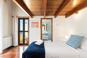 Ein Schlafzimmer mit einem Bett, einem Nachttisch, einem Spiegel, einem Fenster und einer Tür, die auf einen Balkon führt.
