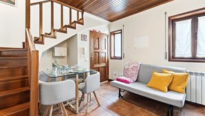 A modern interior with a staircase, a dining area, a sofa, and a window. - GuestReady - Casa Âncora (Aveiro)