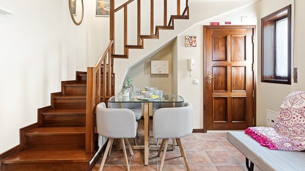 A staircase leading to a dining area with a glass table and two chairs. - GuestReady - Casa Âncora (Aveiro)