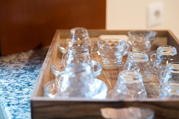 A tray of clear glass tumblers and cups on a wooden surface.