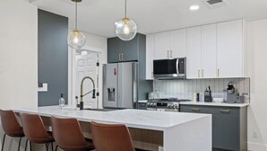 A modern kitchen with a large island, stainless steel appliances, and pendant lighting. - Game, Grill & Lounge Modern S Austin Hangout House Sleeps 10 - Mins to SoCo (Austin)