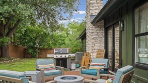 An outdoor patio with a stone chimney, a grill, and lounge chairs. - Game, Grill & Lounge Modern S Austin Hangout House Sleeps 10 - Mins to SoCo (Austin)
